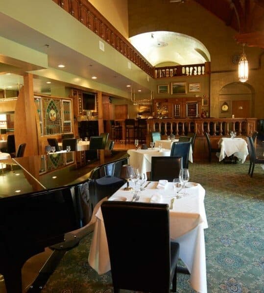 table for two near a black grand piano in a large formal dining area