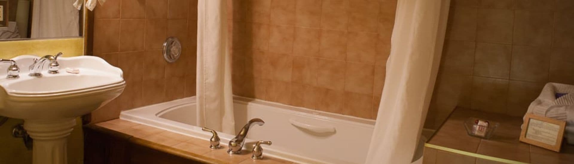 A cozy bathroom with a bathtub, shower curtains, and a pedestal sink.