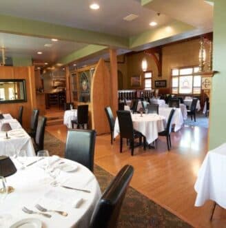 black chairs set around dining tables covered with white tableclothes in a formal dining room